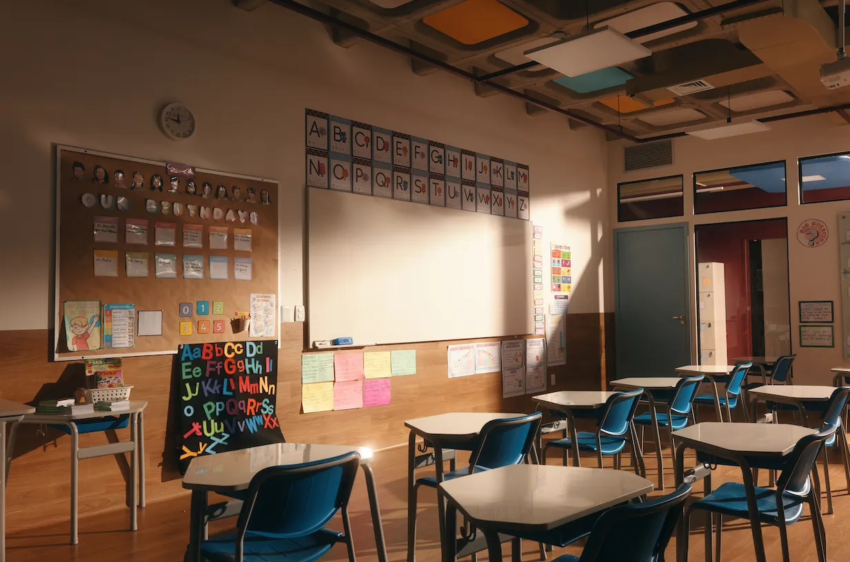 Sala de aula com alfabeto ilustrado acima do quadro branco e mural de aniversários da turma