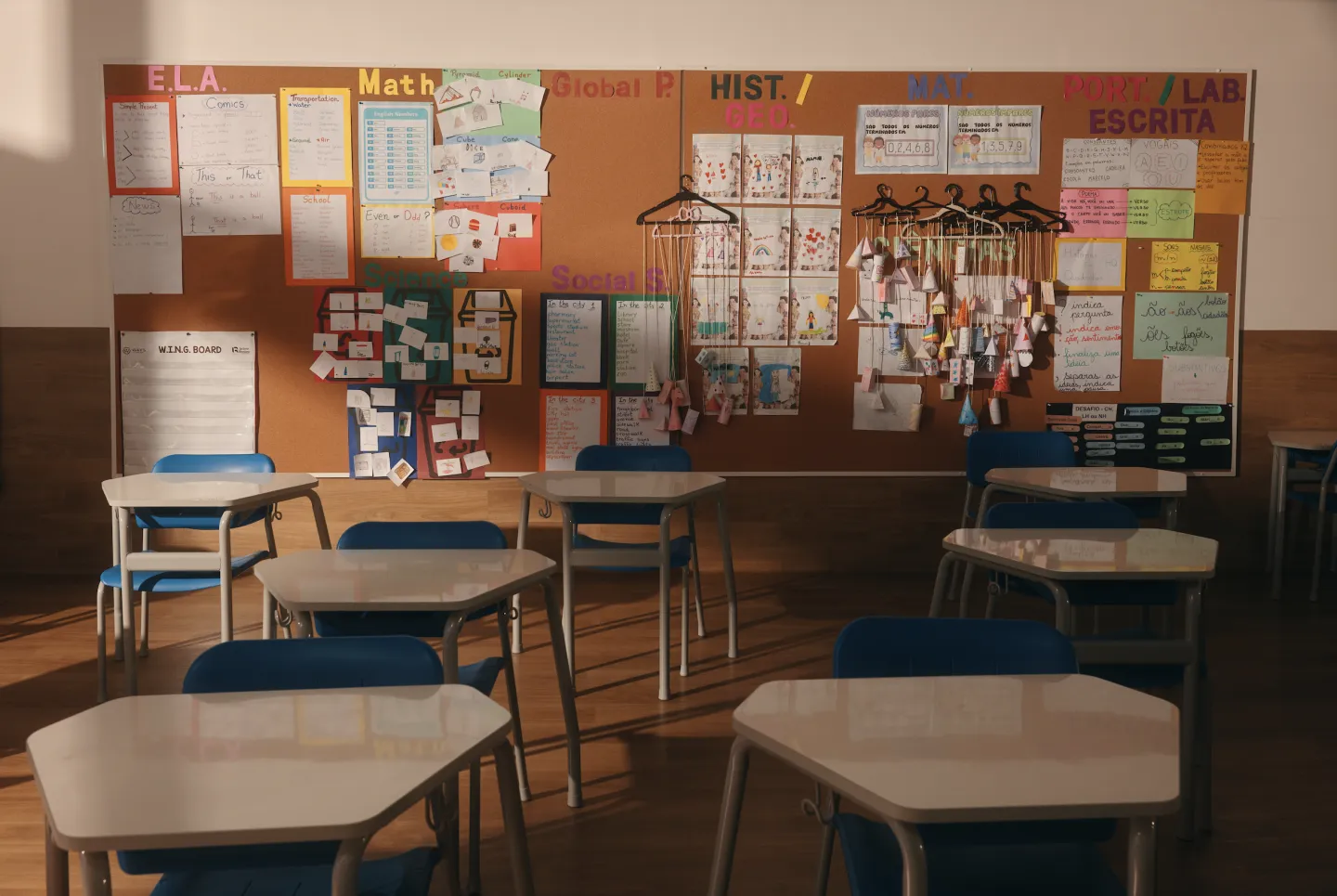 Sala de aula com murais de E.L.A., Math, Science, Português e Matemática, em inglês e português